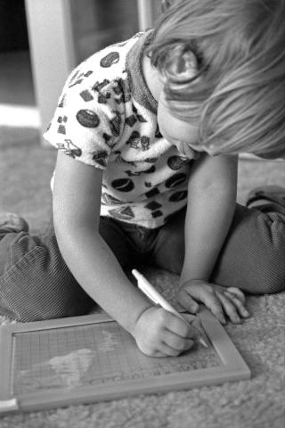 à 4 ans déjà je tirais la langue pour m'appliquer encore plus. Anne, 4 ans, écrit sur son ardoise magique.